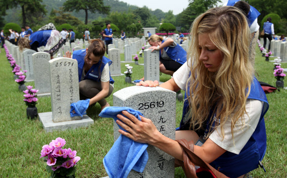 9일 오전 서울 동작동 국립서울현충원에서 UN 참전국 청소년 평화캠프 참가자들이 참전용사 묘역에서 묘비를 닦고 있다. 연합뉴스