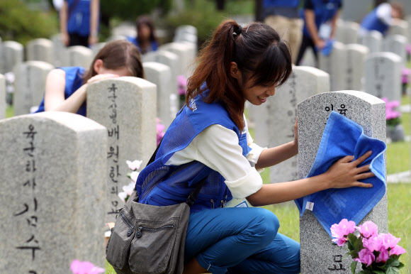 9일 오전 서울 동작동 국립서울현충원에서 UN 참전국 청소년 평화캠프 참가자들이 참전용사 묘역에서 묘비를 닦고 있다. 연합뉴스