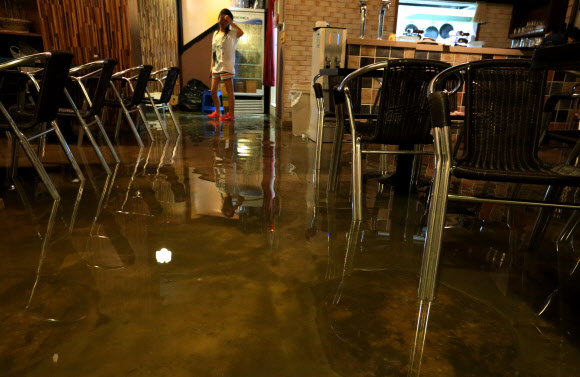 13일 서울 서대문구 연세로5길의 폭우로 침수된 한 지하카페에서 한 사람이 가득찬 물을 보고 망연자실해하고 있다. 연합뉴스
