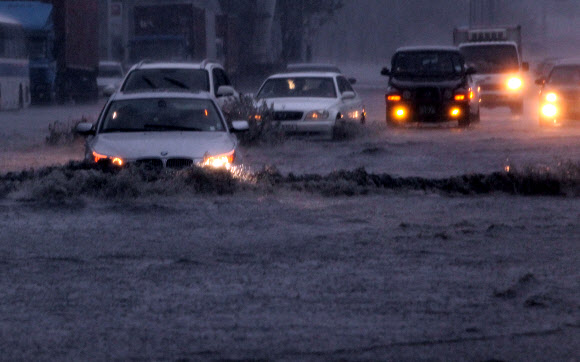 부산에 호우경보가 발령되고 시간당 최대 50㎜의 장대비가 내린 15일 해운대구 우동 센텀시티에서 차량들이 전조등을 켜고 침수된 도로를 겨우 빠져나가고 있다. 연합뉴스