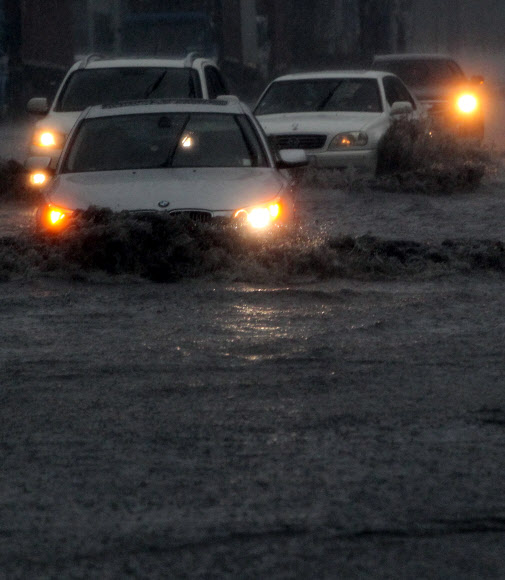 부산에 호우경보가 발령되고 시간당 최대 50㎜의 장대비가 내린 15일 해운대구 우동 센텀시티에서 차량들이 전조등을 켜고 침수된 도로를 겨우 빠져나가고 있다.  연합뉴스