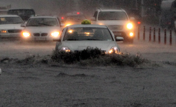 부산에 호우경보가 발령되고 시간당 최대 50㎜의 장대비가 내린 15일 해운대구 우동 센텀시티에서 차량들이 전조등을 켜고 침수된 도로를 겨우 빠져나가고 있다.  연합뉴스
