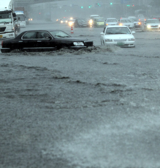 부산에 호우경보가 발령되고 시간당 최대 50㎜의 장대비가 내린 15일 해운대구 우동 센텀시티에서 차량들이 전조등을 켜고 침수된 도로를 겨우 빠져나가고 있다.  연합뉴스