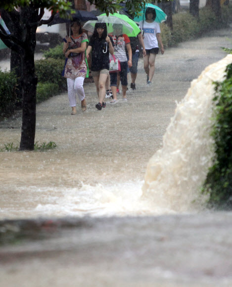 부산에 호우경보가 발령되고 시간당 최대 50㎜의 장대비가 내린 15일 해운대구 우동에서 시민들이 물바다가 된 보행로를 걷고 있다.   연합뉴스