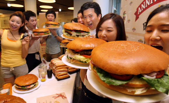 17일 오전 서울 동대문구  CJ 제일제당센터 1층에서 열린 ‘직원 빅버거 먹기 대회’에서 모델과 임직원들이 햄버거를 들고 포즈를 취하고 있다. 연합뉴스