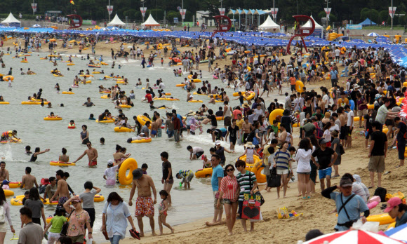 22일 부산 해운대해수욕장을 찾은 피서객들이 물놀이를 즐기거나 파라솔 아래에서 더위를 식히고 있다. 이날 해운대해수욕장에는 25만명의 피서객들이 몰려 더위를 식혔다. 연합뉴스