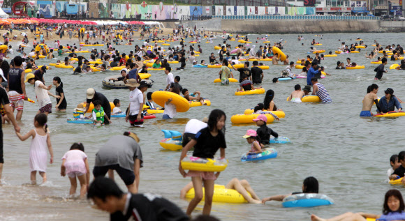 22일 부산 해운대해수욕장을 찾은 피서객들이 물놀이를 즐기거나 파라솔 아래에서 더위를 식히고 있다. 이날 해운대해수욕장에는 25만명의 피서객들이 몰려 더위를 식혔다.  연합뉴스