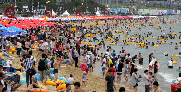 22일 부산 해운대해수욕장을 찾은 피서객들이 물놀이를 즐기거나 파라솔 아래에서 더위를 식히고 있다. 이날 해운대해수욕장에는 25만명의 피서객들이 몰려 더위를 식혔다. 연합뉴스