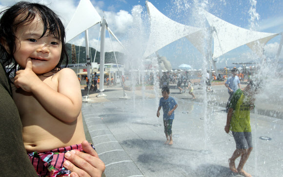 24일 오전 전남 여수엑스포 행사장에서 한 어린아이가 분수옆에서 더위를 식히고 있다. 연합뉴스