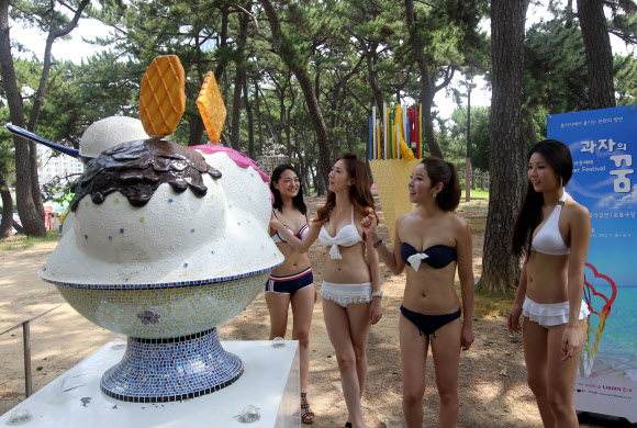 26일 부산 해운대해수욕장 송림공원에서 수영복 차림의 여성들이 크라운-해태제과가 마련한 현대 미술작품을 감상하고 있다. 연합뉴스