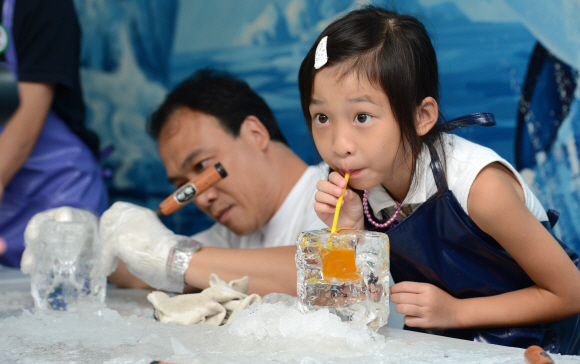 아이스갤러리에서 한국관광을 온 한 홍콩 어린이가 직접 만든 얼음컵에 음료수를 담아서 마시고 있다.