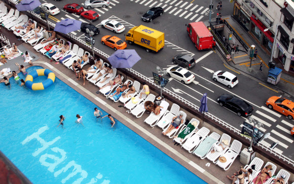 찜통더위가 이어지고 있는 가운데 27일 서울 이태원 해밀턴호텔 옥상 수영장을 찾은 시민들이 더위를 즐기고 있다.  연합뉴스