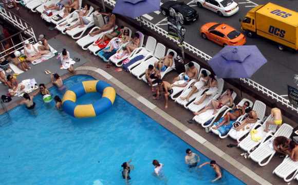 찜통더위가 이어지고 있는 가운데 27일 서울 이태원 해밀턴호텔 옥상 수영장을 찾은 시민들이 더위를 즐기고 있다.  연합뉴스