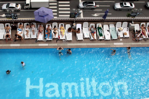 찜통더위가 이어지고 있는 가운데 27일 서울 이태원 해밀턴호텔 옥상 수영장을 찾은 시민들이 더위를 즐기고 있다.  연합뉴스
