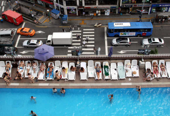 찜통더위가 이어지고 있는 가운데 27일 서울 이태원 해밀턴호텔 옥상 수영장을 찾은 시민들이 더위를 즐기고 있다.  연합뉴스