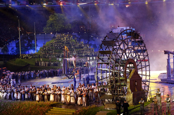 지구촌 최대 스포츠축제가 될 제30회 런던하계올림픽이 28일 영국 런던 북동부 리밸리의 올림픽스타디움에서 화려한 막을 올렸다. ‘경이로운 영국(Isles of Wonder)’이라는 주제로 열린 개막식은 대니 보일 감독이 연출을 맡아 산업화의 진통에서 회복해 미래를 바라보는 농촌의 이야기를 담았다. 광부, 제철소 노동자, 직공, 기술자 차림을 한 연기자들이 산업혁명의 선구자인 영국이 세계의 공장 역할을 하던 시기를 형상화한 2막 공연이 펼쳐지고 있다. 런던 연합뉴스