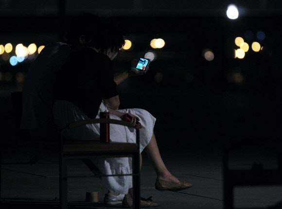 런던올림픽 한국대표팀의 금빛사냥 첫 날인 29일 새벽, 열대야를 피해 한강 시민공원에 나온 시민들이 스마트폰으로 남자사격 진종오의 금메달 소식을 보고 있다. 이날 4개의 금메달을 노렸던 한국은 진종오의 금메달과 박태환의 400m 은메달에 만족해야 했다. 연합뉴스