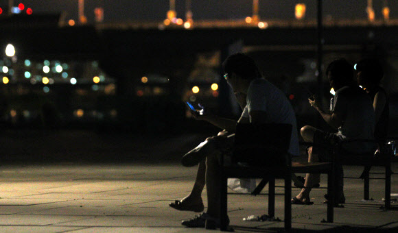 런던올림픽 한국대표팀의 금빛사냥 첫 날인 29일 새벽, 열대야를 피해 한강 시민공원에 나온 시민들이 스마트폰으로 남자사격 진종오의 금메달 소식을 보고 있다. 이날 4개의 금메달을 노렸던 한국은 진종오의 금메달과 박태환의 400m 은메달에 만족해야 했다. 연합뉴스