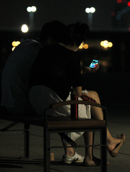 런던올림픽 한국대표팀의 금빛사냥 첫 날인 29일 새벽, 열대야를 피해 한강 시민공원에 나온 시민들이 스마트폰으로 남자사격 진종오의 금메달 소식을 보고 있다. 이날 4개의 금메달을 노렸던 한국은 진종오의 금메달과 박태환의 400m 은메달에 만족해야 했다. 연합뉴스