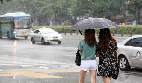 30일 오후 서울 중구 삼성생명 앞 도보에서 시민들이 갑자기 비가 내리자 우산을 들고 바삐 걸어가고 있다. 연합뉴스