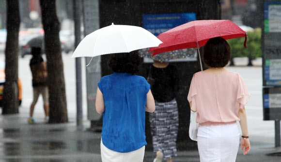 30일 오후 서울 중구 삼성생명 앞 도보에서 시민들이 갑자기 비가 내리자 우산을 들고 바삐 걸어가고 있다.  연합뉴스
