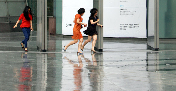 30일 오후 서울 중구 삼성생명 앞 도보에서 시민들을 비를 피해 건물로 뛰어들어 가고 있다. 연합뉴스