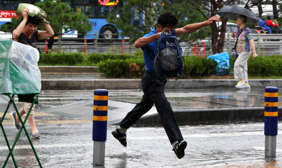 무더위를 식혀주는 ‘깜짝’ 소나기가 내리던 30일 오전 서울시 중구 봉래동 서울역 광장에서 우산이 없는 시민이 물웅덩이를 뛰어 넘고 있다.  연합뉴스