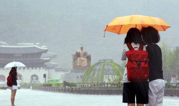 갑자기 많은 양의 소나기가 내린 30일 오전 서울 광화문에 시민들이 우산을 쓴 채 신호를 기다리고 있다. 연합뉴스