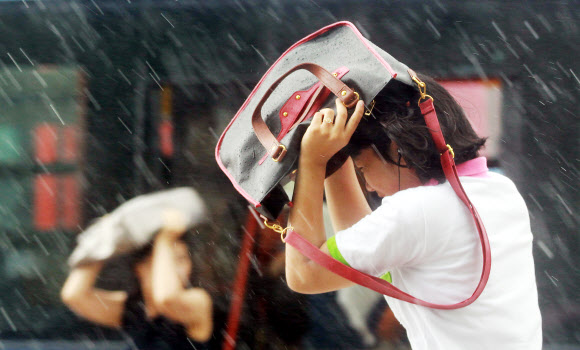 갑자기 많은 양의 소나기가 내린 30일 오전 서울 광화문에 한 시민이 우산 대신 가방으로 비를 막아보고 있다.  연합뉴스