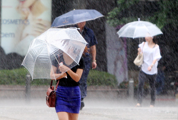 30일 오전 서울 중구 예금보험공사앞 도보에서 시민들이 갑작스레 쏟아진 비에 놀라 우산을 들고 뛰어가고 있다.  연합뉴스