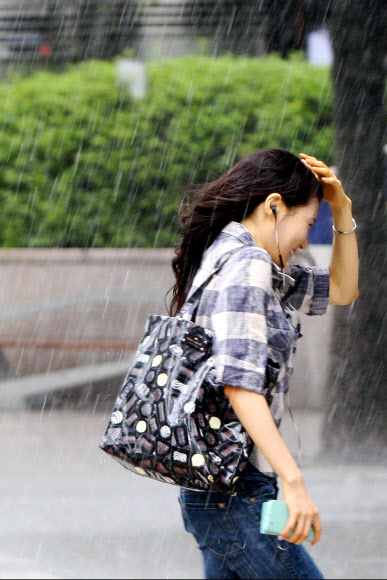 30일 오전 서울 중구 예금보험공사 앞 도보에서 한 시민이 갑작스레 쏟아진 비에 손으로 머리를 가리고 뛰어가고 있다. 연합뉴스