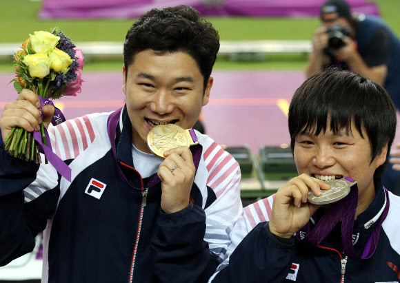 2012 런던올림픽에서 남자 50ｍ 권총 2연패를 달성한 진종오와 은메달을 차지한 최영래가 5일 오후(한국 시간) 영국 런던 그리니치파크의 왕립 포병대 기지 사격장에서 우승을 차지한 후 시상대에 올라 각각 메달을 깨물어보고 있다. 연합뉴스