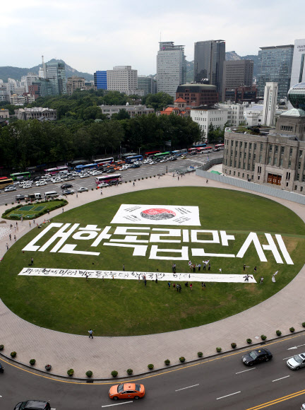 광복절을 하루 앞둔 14일 오후 서울광장에서 한국 서예 퍼포먼스 김동욱 고문이 대형 태극기 그리기 퍼포먼스를 하고 있다. 연합뉴스