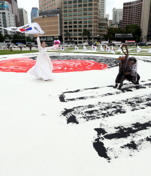 광복절을 하루 앞둔 14일 오후 서울광장에서 한국 서예 퍼포먼스 김동욱 고문이 대형 태극기 그리기 퍼포먼스를 하고 있다. 연합뉴스
