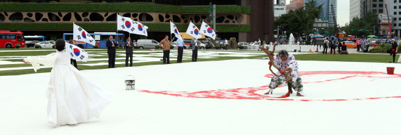 광복절을 하루 앞둔 14일 오후 서울광장에서 한국 서예 퍼포먼스 김동욱 고문이 대형 태극기 그리기 퍼포먼스를 하고 있다. 연합뉴스