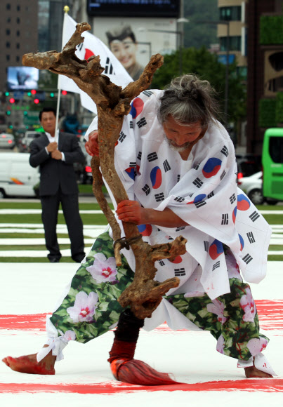 광복절을 하루 앞둔 14일 오후 서울광장에서 한국 서예 퍼포먼스 김동욱 고문이 대형 태극기 그리기 퍼포먼스를 하고 있다. 연합뉴스