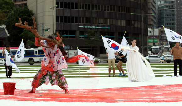 광복절을 하루 앞둔 14일 오후 서울광장에서 한국 서예 퍼포먼스 김동욱 고문이 대형 태극기 그리기 퍼포먼스를 하고 있다. 연합뉴스
