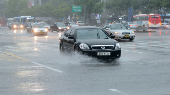 중부지방에 폭우가 내린 15일 서울 광화문에서 차량들이 물을 튀기며 빗물에 잠긴 도로 위를 달리고 있다.  손형준기자 boltagoo@seoul.co.kr
