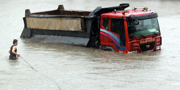 서울지역에 호우경보가 내려진 15일 오후 구조대원이 동부간선도로 월릉교 인근 중랑천에 잠긴 덤프트럭에 사람이 타고 있는지 확인하고 있다.   연합뉴스