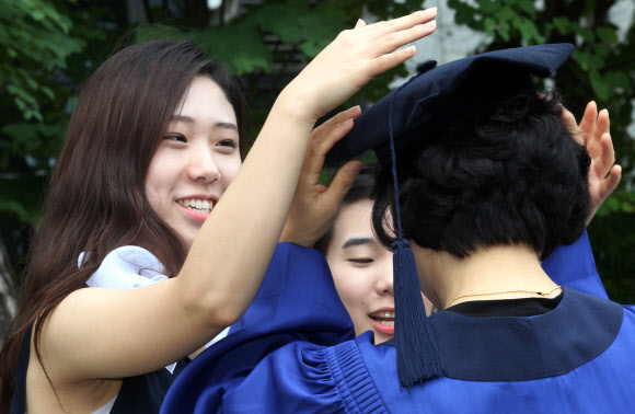 17일 오전 서울 용산구 숙명여대에서 코스모스 졸업을 맞은 한 학생이 어머니에게 학사모를 씌워드리고 있다.  연합뉴스