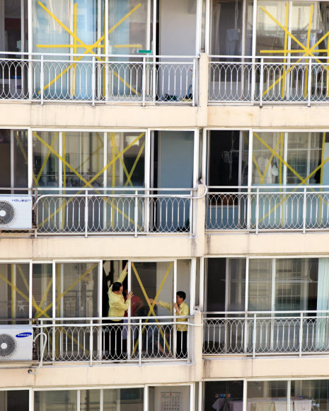 제15호 태풍 ‘볼라벤(BOLAVEN)’이 북상 중인 가운데 26일 오후 목포시 공무원들이 옥암동 금호 아파트 유리창에 테이프를 붙이고 있다. 이 아파트는 태풍 내습 때 강풍에 대형 유리창이 깨지는 피해를 봤다. 상자 테이프를 이용, 가로 세로로 붙이거나 신문지에 물을 묻혀 붙여 놓으면 강풍에도 유리창이 깨지지 않고 잘 버틴다. 시는 강풍에 파손 위험이 있는 일부 아파트에서 테이핑 작업을 했다. 연합뉴스