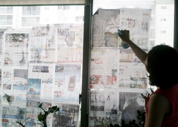 제15호 태풍 ‘볼라벤’이 북상 중인 가운데 28일 오전 대전시 서구 둔산동 아파트에서 한 주부가 베란다 유리창에 신문지를 붙이고 있다. 연합뉴스