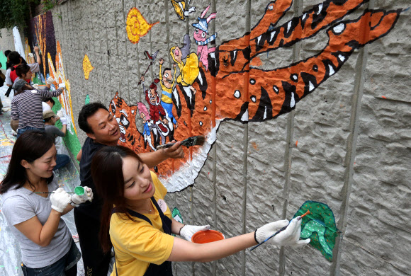 9일 서울 성동구 사근초등학교 담장에 학생들이 벽화를 그리고 있다. 성동구는 ‘공감과 소통을 위한 골목길 만들기’ 사업으로 사근동을 선정하고 주민들의 의견을 모아 역사와 문화가 있는 벽화그리기를 진행했다.   연합뉴스
