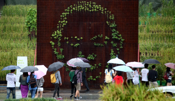가을비가 내린 13일, 서울 세종문화회관 계단 설치된 나무 조형물을 시민들이 보고 있다.  연합뉴스