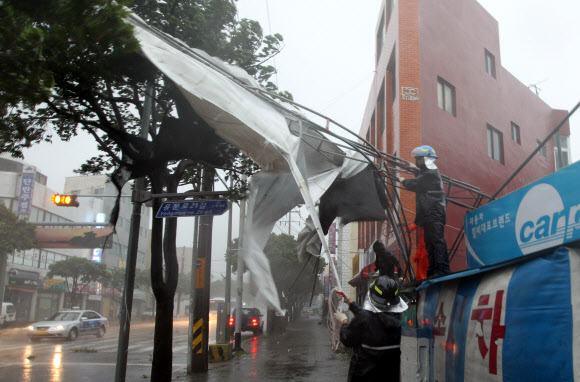 17일 오전 제16호 태풍 ‘산바’가 제주를 강타한 가운데 제주시 용담동에서 119구조대원들이 강풍에 날린 천막을 안전하게 조치하고 있다.  연합뉴스