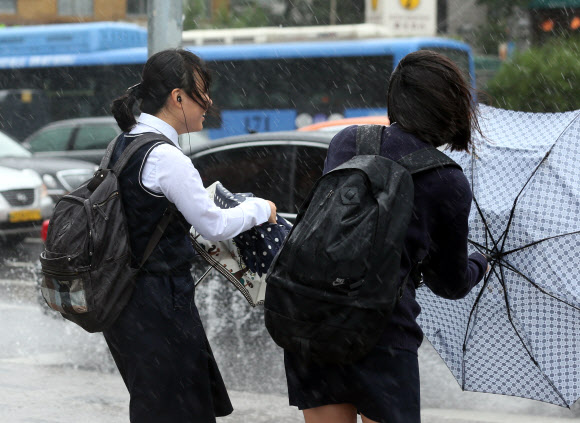 태풍 ‘산바’로 서울지역 각급 학교에 조기 하교 권고가 내린 17일 오후 서울 종로구 안국동 풍문여고 앞에서 학생들이 거친 비바람에 당황하고 있다.  연합뉴스