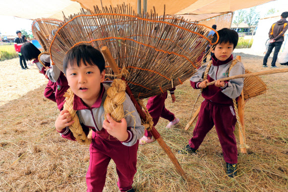 전북 김제시 부량면 벽골제 일대에서 열리는 김제지평선축제장에서 꼬마들이 12일 물건을 옮기는 지게를 체험하고 있다. 국내 최대의 농경체험 지평선축제는 14일까지 계속된다.  연합뉴스