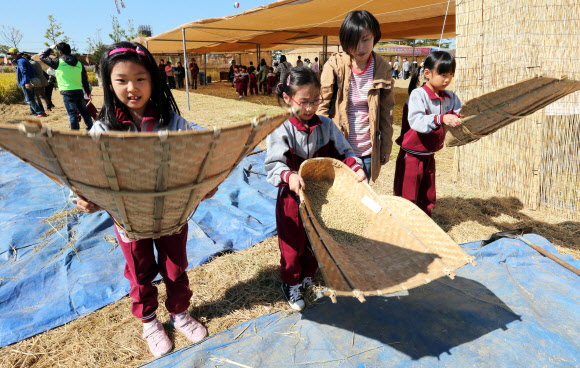 전북 김제시 부량면 벽골제 일대에서 열리는 김제지평선축제장에서 꼬마들이 12일 쌀에서 돌을 골라냈던 ‘키’를 체험하고 있다. 국내 최대의 농경체험 지평선축제는 14일까지 계속된다. 연합뉴스