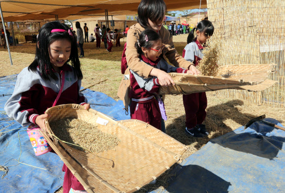 전북 김제시 부량면 벽골제 일대에서 열리는 김제지평선축제장에서 꼬마들이 12일 쌀에서 돌을 골라냈던 ‘키’를 체험하고 있다. 국내 최대의 농경체험 지평선축제는 14일까지 계속된다. 연합뉴스