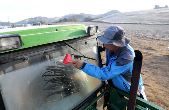 15일 강원 평창군 대관령 지역의 최저기온이 올해 가을 들어 가장 낮은 영하 1도까지 떨어졌다. 대관령 지역의 농민이 서리가 잔뜩 내린 들판에서 가을걷이에 앞서 농기계 창에 얼어 붙어 있는 얼음을 제거하고 있다.  연합뉴스